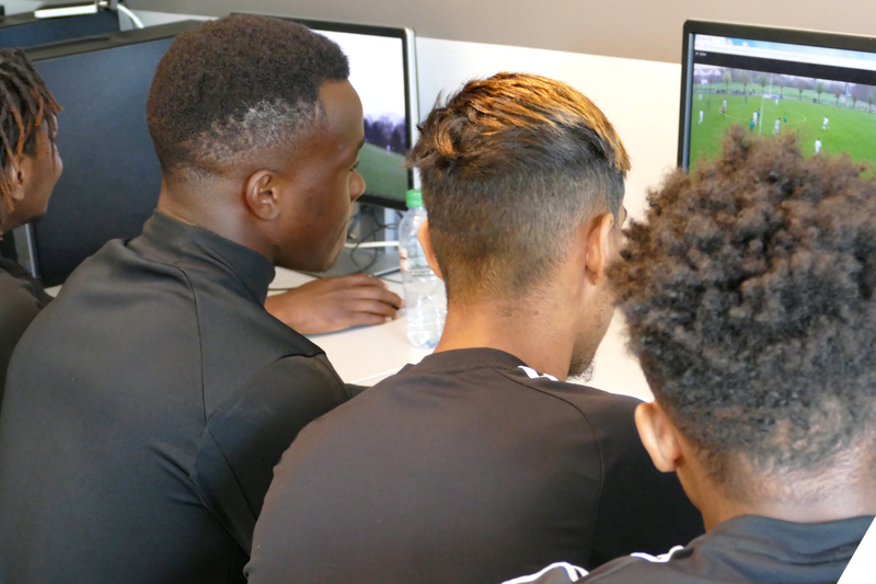 ノート PC でリプレイ動画を見ているサッカーチーム
